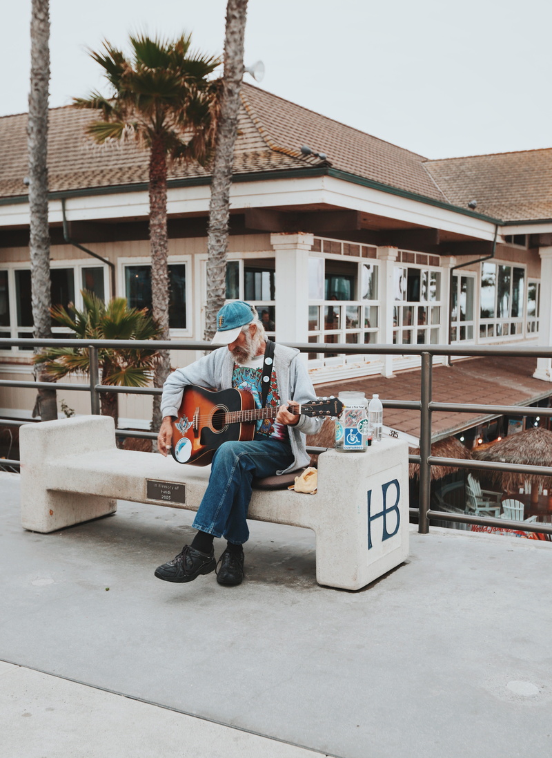 building, outdoor, huningtonbeach, sits, one person, white, outdoors, sidewalk, music, daytime, beard, young adult, day, palm tree, disabled, guitar, brown