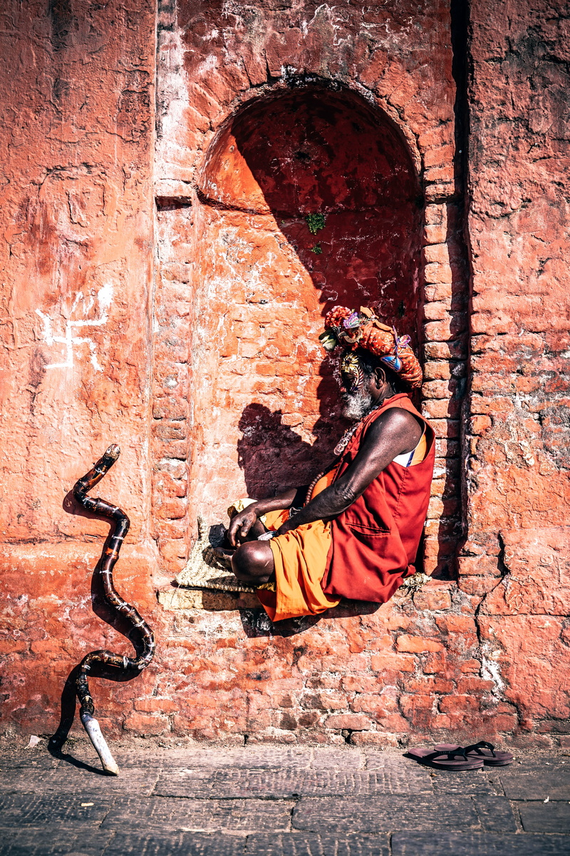 wall, building exterior, leisure activity, built structure, old man, outdoors, full length, lifestyles, brown, adult, sit, guy, sandal, traditional clothing