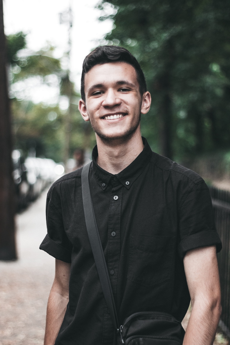 young men, city, new york, standing, happiness, all black, portrait, looking at camera, leisure activity, day, outdoors, 1.4, waist up, ny, smile, one person