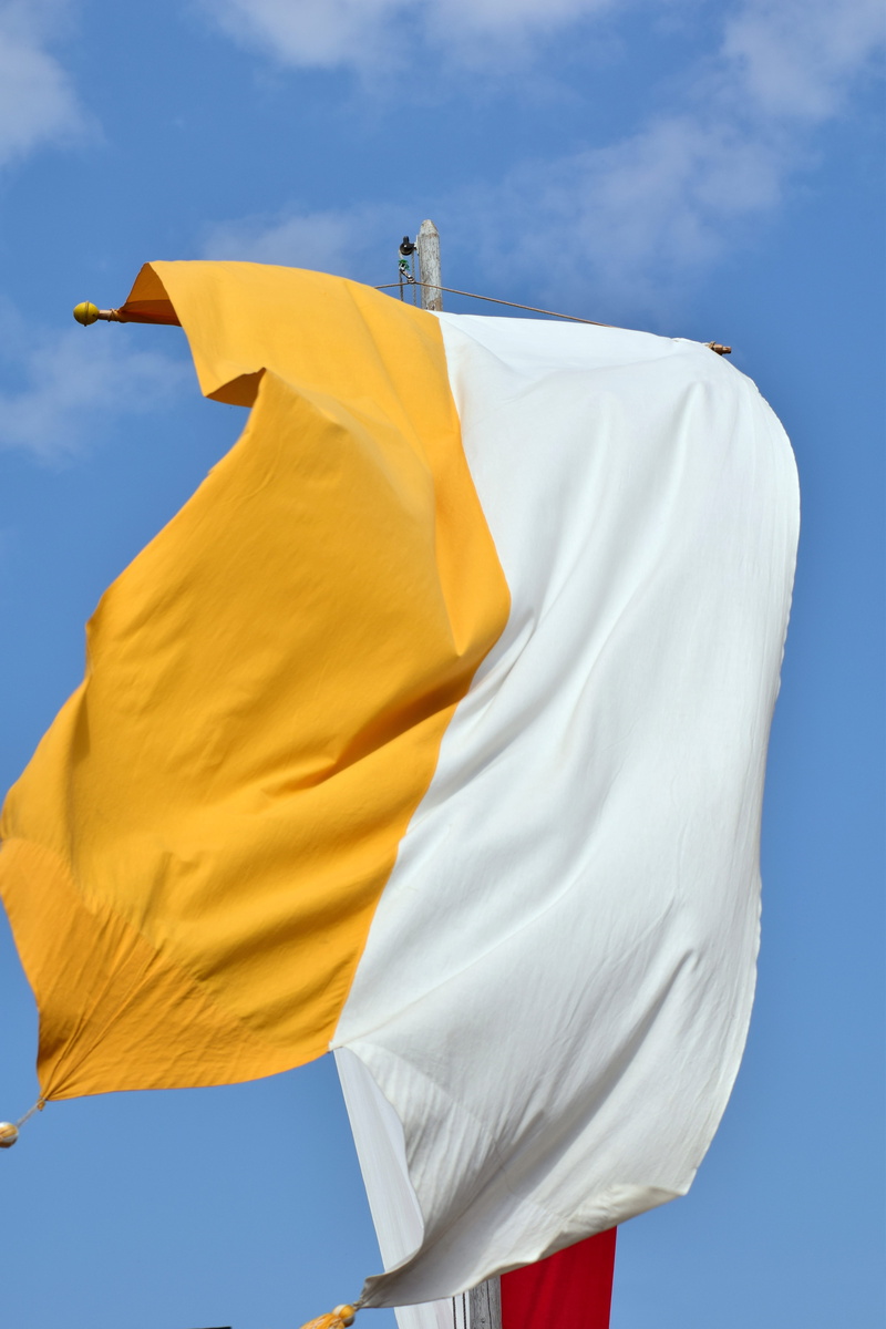 low angle view, clean, drying, tradition, outdoors, yellow, environment, day, sky, corpus christi, blue, christianity, white, hanging, wind, faith, church