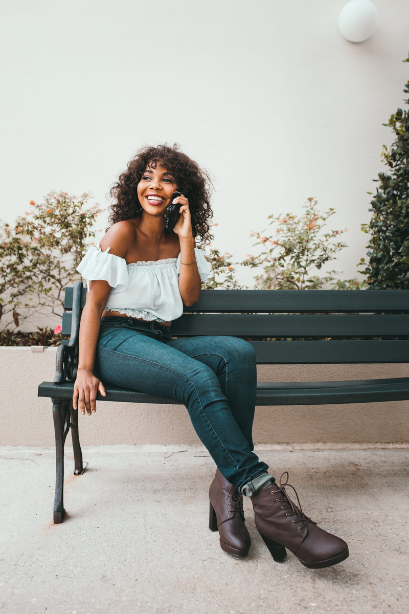 woman, smiling, day, urban, phone, 2K, now, seat, can, sat, sitting, looking at camera, green, smile, female, bench, wooden, hear, hairstyle, boutiquer