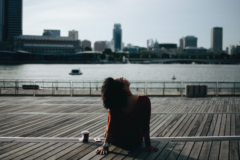 building, office building exterior, bench, break, leisure activity, relaxation, ocean, one person, sitting, skyscraper, river, singapore, peaceful, female