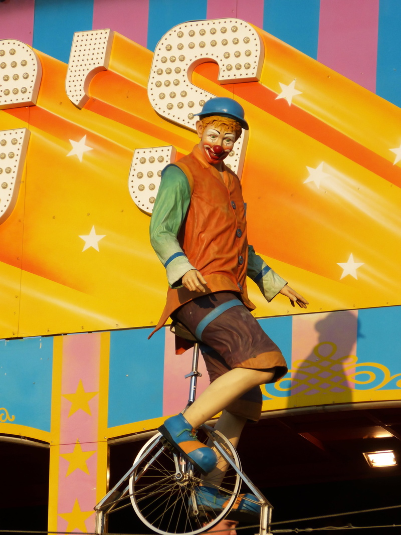 leisure activity, mode of transportation, one person, outdoors, circus, yellow, riding, fair, young adult, casual clothing, looking away, unicycle, transportation