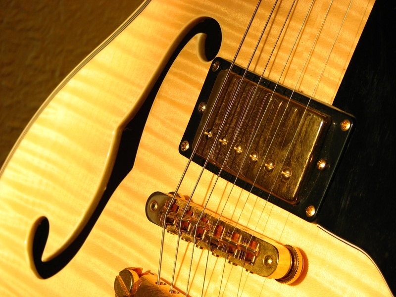 guitar, golden yellow, close-up, woodwind instrument, wind instrument, strings, photo, indoors, instrument, black, musical equipment, acoustic guitar, still life