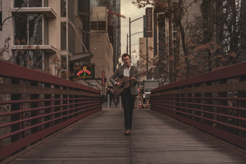 lifestyles, stringed instrument, instrument, bridge, leisure activity, city, holding, standing, adult, architecture, young adult, built structure, string instrument