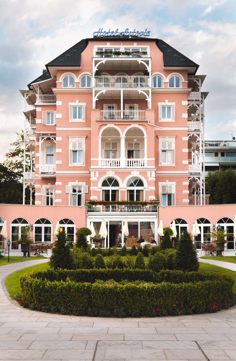 sky, plant, wes anderson, 5K, hotel, building, pink, building exterior, hedge, window, austria, day, sunlight, residential district, sea, no people, 70s