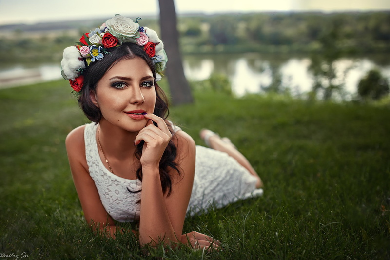 front view, brunette, beautiful woman, sitting, outdoors, plant, one person, river, looking away, leisure activity, nature, women, smiling, wearing flowers