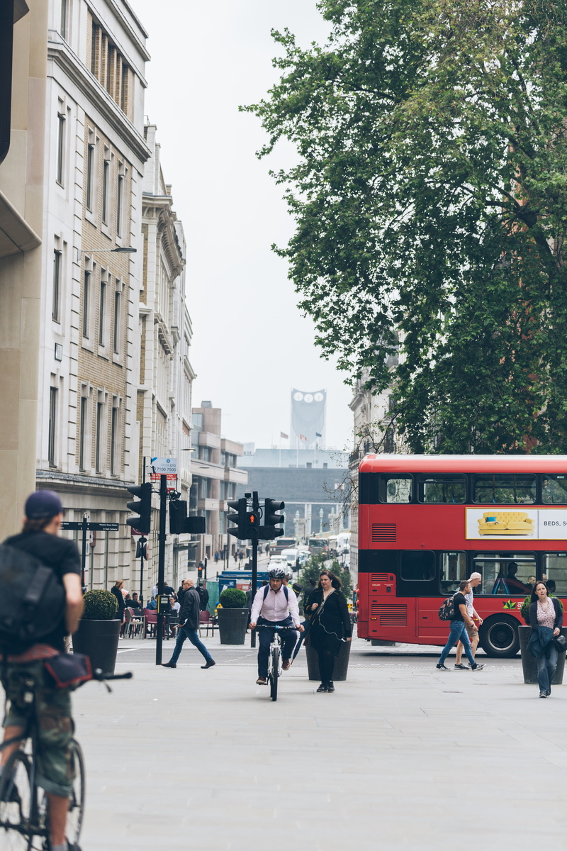 outdoors, riding, bicycle, day, tree, men, building, land vehicle, bus, building exterior, near, architecture, daytime, group of people, white, 5K, walking