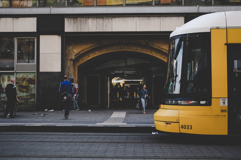 mode of transportation, pavement, yellow, rail transportation, archway, urban, day, transport, adult, men, land vehicle, waiting, building exterior, outdoors