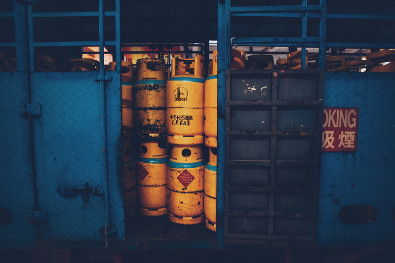 truck, non-western script, pipe - tube, tanks, container, text, propane, beside, industry, script, yellow, sign, architecture, tank, indoors, orange, metal