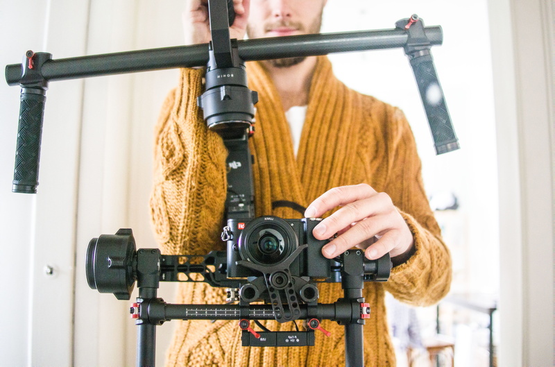 front view, standing, photographer, one person, autumn, industry, sweater, videographer, man, gimbal, balance, studio, equipment, adult, hairstyle, focus on foreground