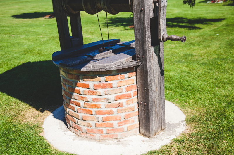 crank, wood - material, handle, wheel, wish, wishing well, focus on foreground, wooden, outdoors, day, sky, grass, mortar, united states, land, metal, green color
