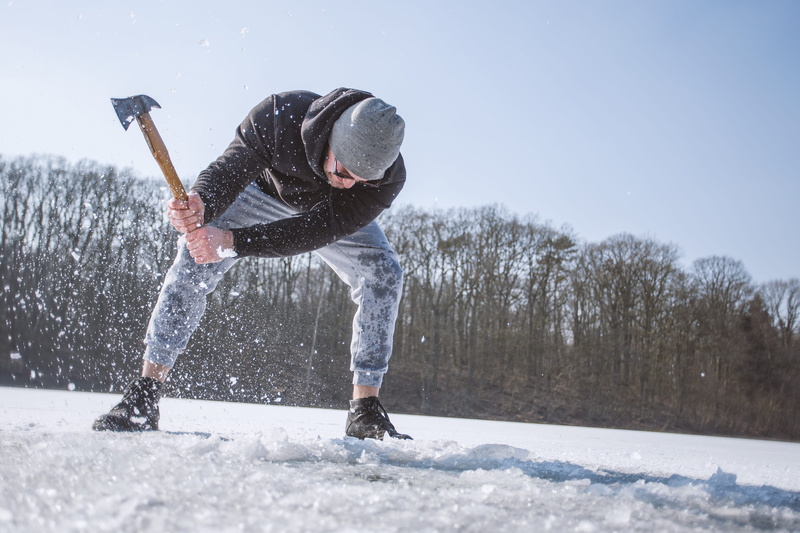 leisure activity, real people, black, warm clothing, axe, bending, adult, person, hooded, enjoyment, cold, one person, weather, leisure, snow, action, gray