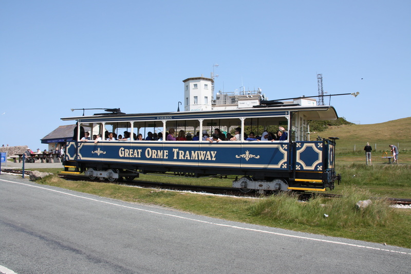 rail transportation, city, road, old tram, clear sky, nature, sign, tram, architecture, land vehicle, blue, on the move, outdoors, bus, travel, great orme