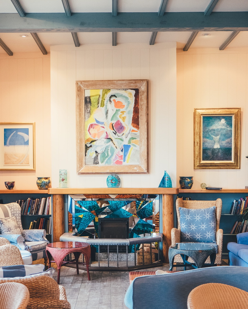fireplace, bay, empty, sofa, hell, domestic room, pillow, picture frame, indoors, chair, no people, table, wicker, seat, paintings, multicolored, home interior