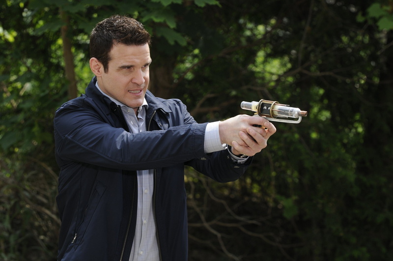 day, handgun, tree, adult, young men, mid adult, gun, mid adult men, warehouse 13, men, holding, waist up, standing, outdoors, aiming, focus on foreground
