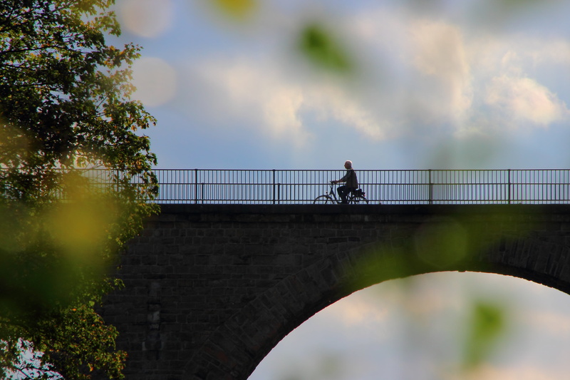 architecture, railing, leisure activity, full length, footbridge, outdoors, bike, lifestyles, more, connection, cloud - sky, adult, tour, one person, cyclists