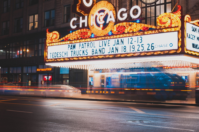 blur, outdoors, sign, city street, blurred motion, speed, signage, motion, night, text, transportation system, lights, architecture, theater, western script
