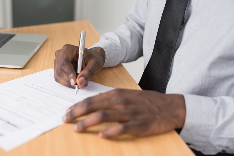 white, indoors, laptop, human body part, midsection, contract, table, pen, wearing, selective focus, person, desk, shirt, writing, business, adult, hands