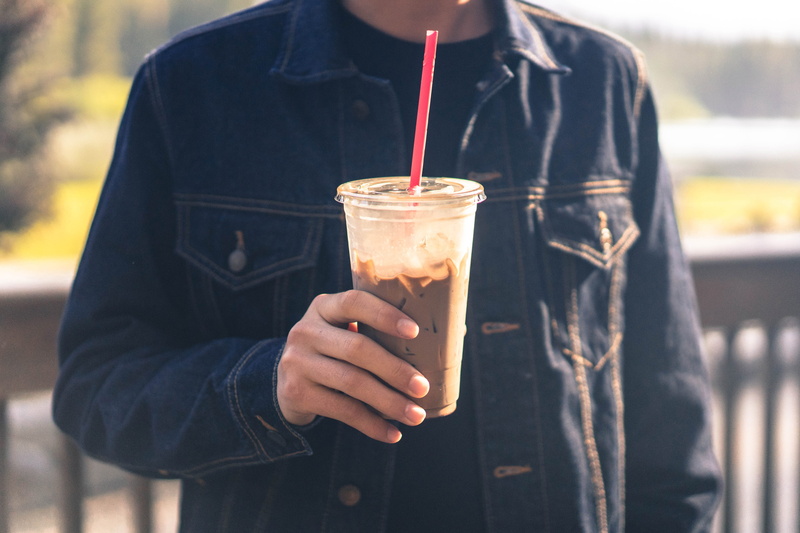 drinking glass, straw, outdoors, holding, front view, one person, household equipment, drink, food, denim, food and Drink, casual clothing, refreshment
