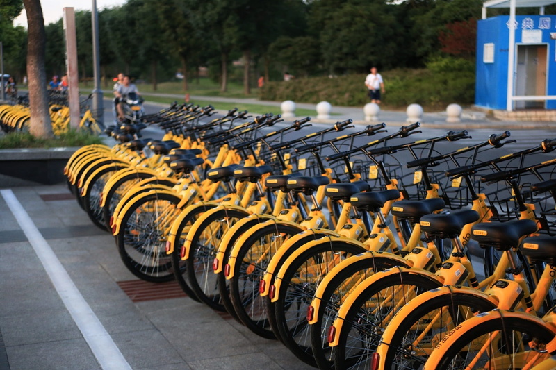 outdoors, focus on foreground, transportation, repetition, road, wheel, shared bike, large group of objects, 1080P, the little yellow car, mode of transportation