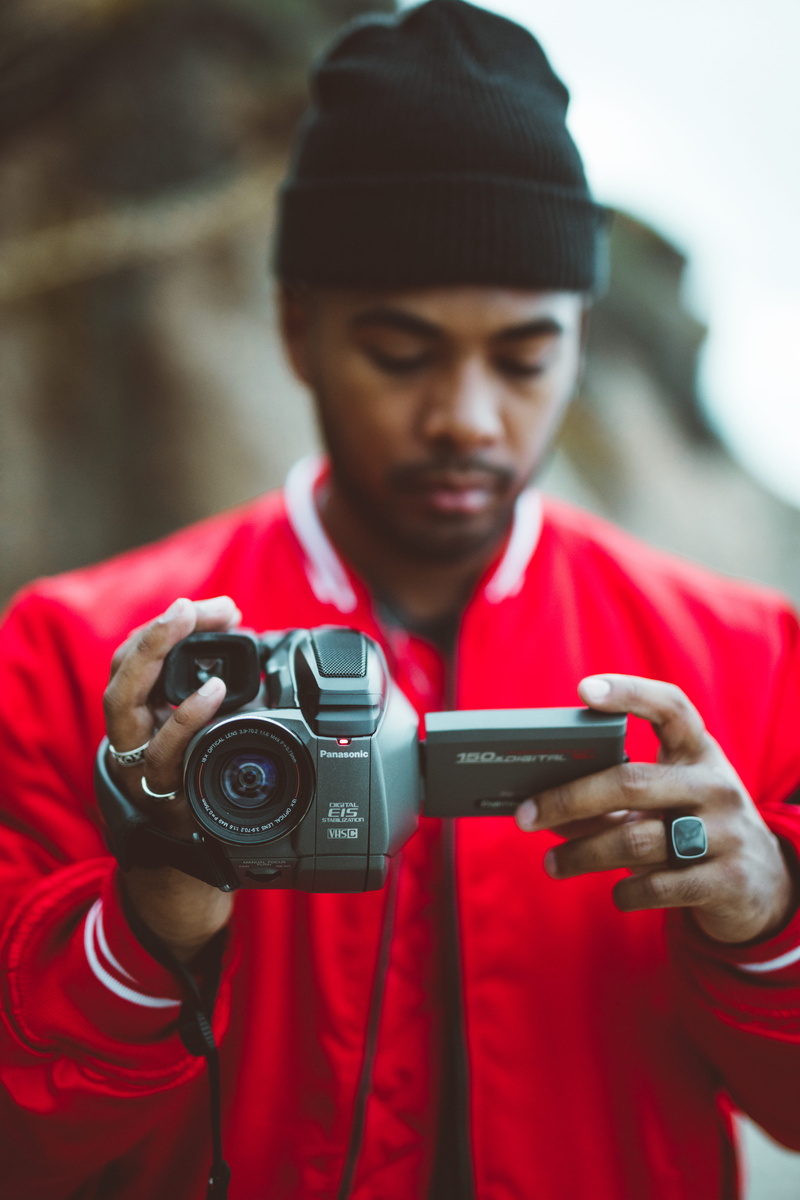sleeve, photographic equipment, young men, skin, digital camera, communication, apparel, video camera, young adult, outdoors, 5K, technology, waist up