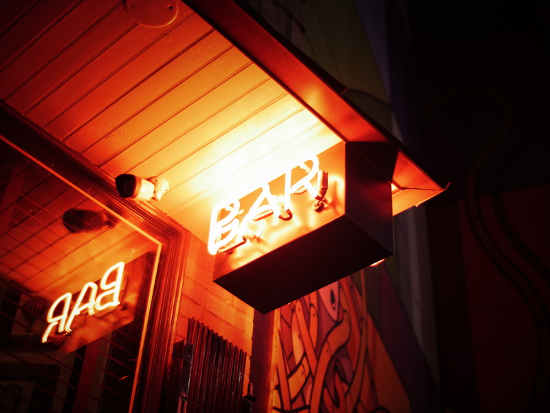 security, signage, indoors, text, red, glowing, sign, low angle view, orange, restaurant, beside, sign, communication, light, bar, camera, nightlife, architecture