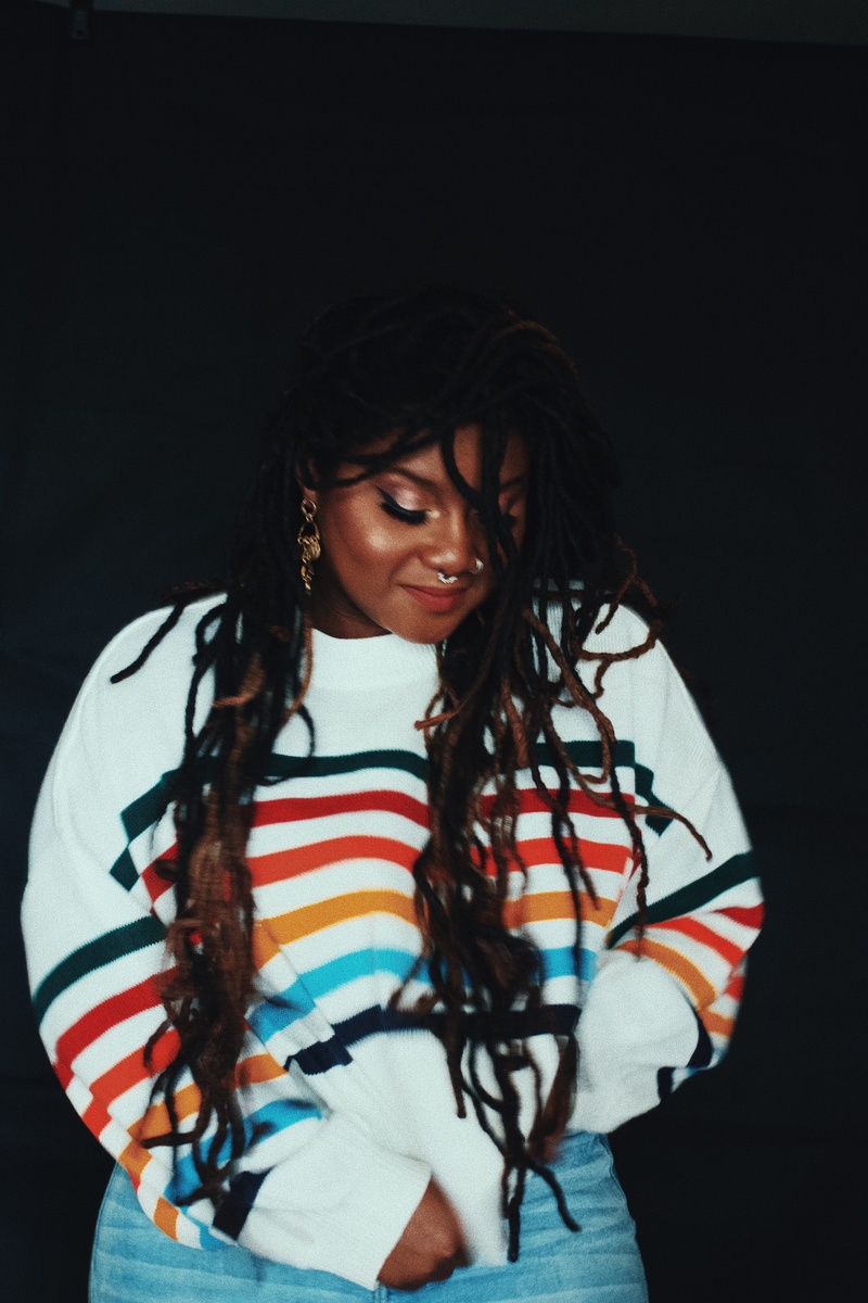 black hair, striped, sleeve, black background, wood, clothing, finger, musical instrument, waist up, blur, long sleeve, plywood, young adult, black woman