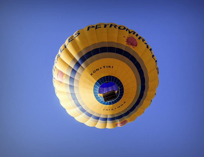 single object, no people, yellow, colorful, low angle view, day, weightless, adventure, mid-air, blue background, built structure, holiday, aerostatic