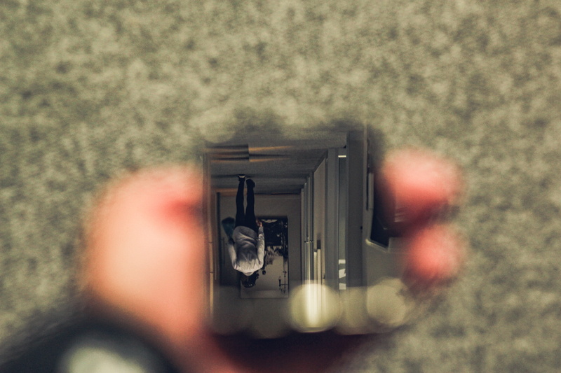 selective focus, close up, one person, apparel, men, holding, sphere, indoors, gun, bottle, beverage, activity, photographer, coat, alcohol, digital camera