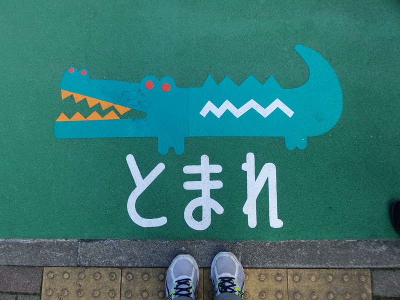 western script, 5K, outdoors, one person, day, real people, japan, human limb, body part, Drawing, human leg, Sign, green color, Crocodile, low section