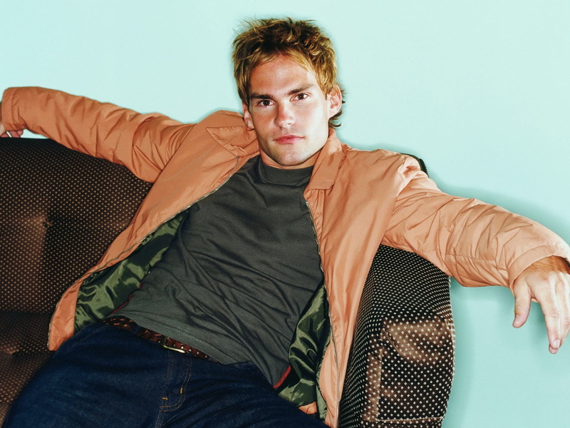 contemplation, arms, jacket, domestic room, looking at camera, young adult, front view, leisure activity, coat, jeans, chair, s, adult, three quarter length