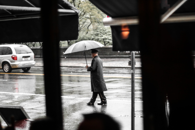 mode of transportation, umbrella, walking, coat, rainy season, valet parking, motor vehicle, one person, architecture, street, car, outdoors, manhattan