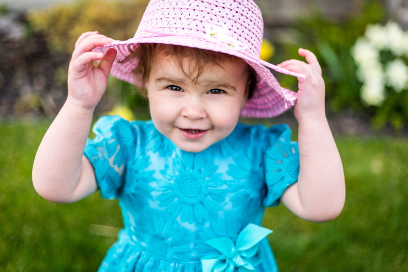 focus on foreground, human arm, cute, day, dress, girl, flowers, cap, front view, portrait, happiness, body part, looking at camera, color, smiling, hand