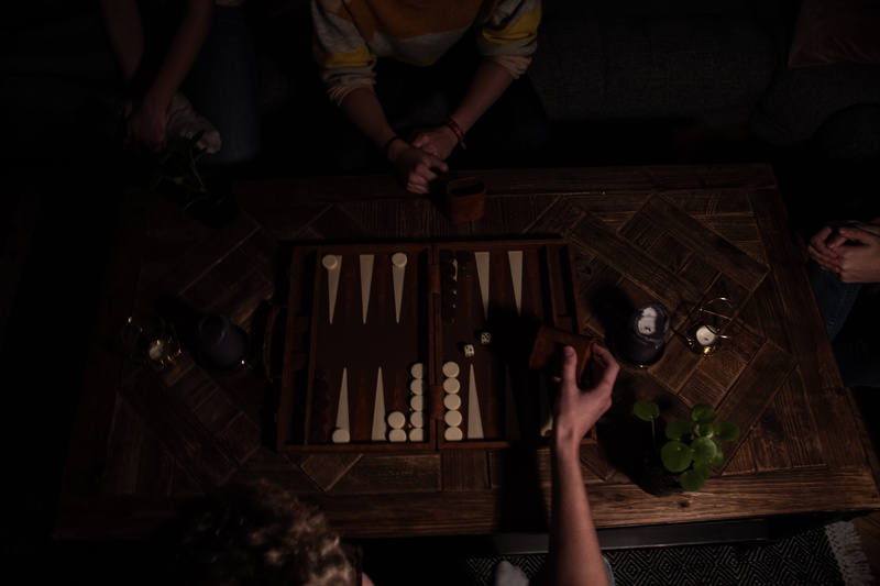 hand, dark, wood - material, adult, high angle view, holding, person, night, board game, human body part, real people, group, indoors, group of people