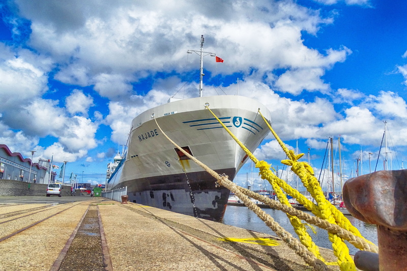 nautical vessel, sailboat, mode of transportation, built structure, building exterior, port, patriotism, nature, sunlight, direction, low angle view, flag