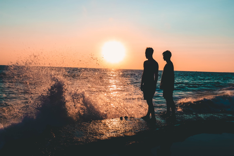 sand, sky, friends, leisure activity, land, ocean, water, togetherness, water splash, beauty in nature, people, standing, real people, nature, backlit