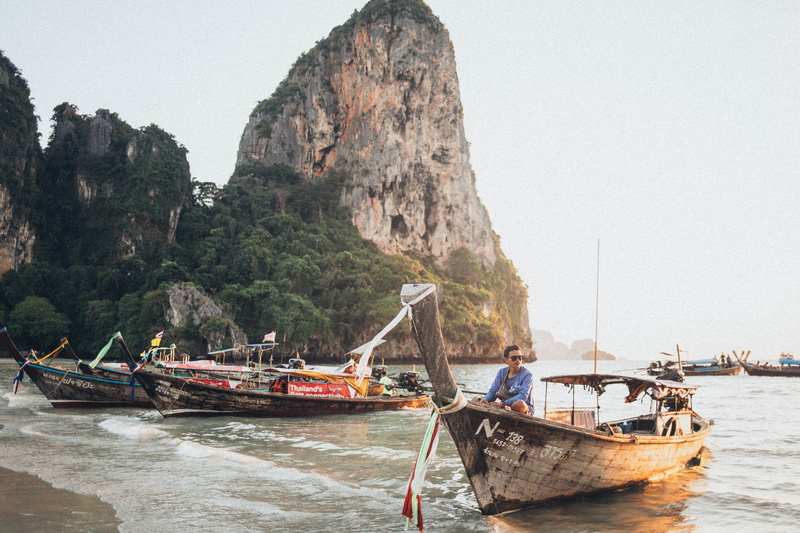 rock formation, land, sky, daylight, mountain, clouds, coast, sunglasses, boats, rock - object, water, transportation system, scenic, fishing boat, sand