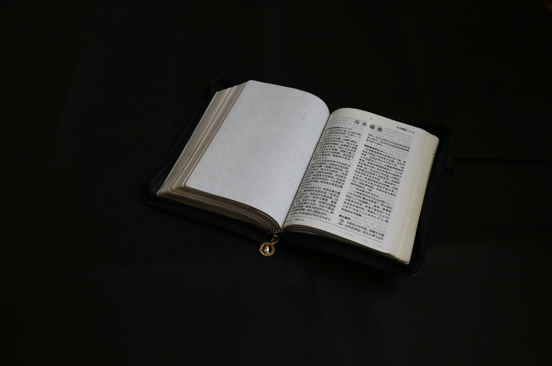 studio shot, bible, text, two objects, black background, 5K, high angle view, page, close-up, no people, book, communication, publication, music, open