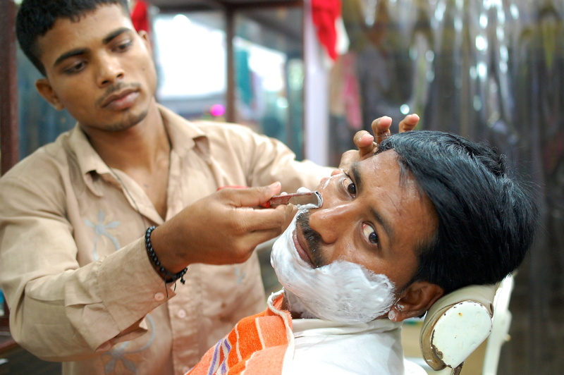 young men, hairdresser, Male, outdoors, focus on foreground, two people, portrait, holding, 2K, Street, India, shaving, front view, barber shop, occupation