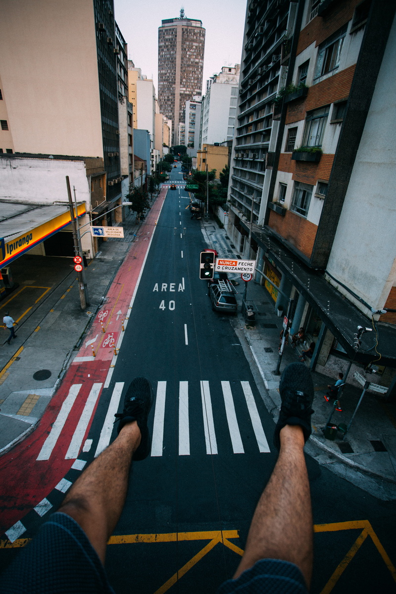 perspective, sign, real people, human body part, facing, city street, built structure, urban, lace, road marking, outdoors, signs, sneakers, cityscape