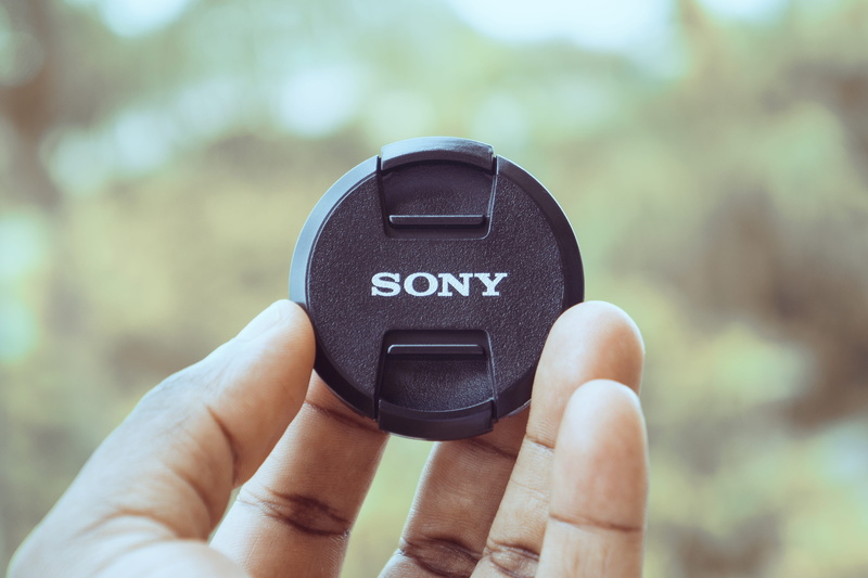 logo, camera lens, black color, day, real people, human, personal accessory, people, human hand, body part, poster, machine, black, person, sony, 5K, car wheel