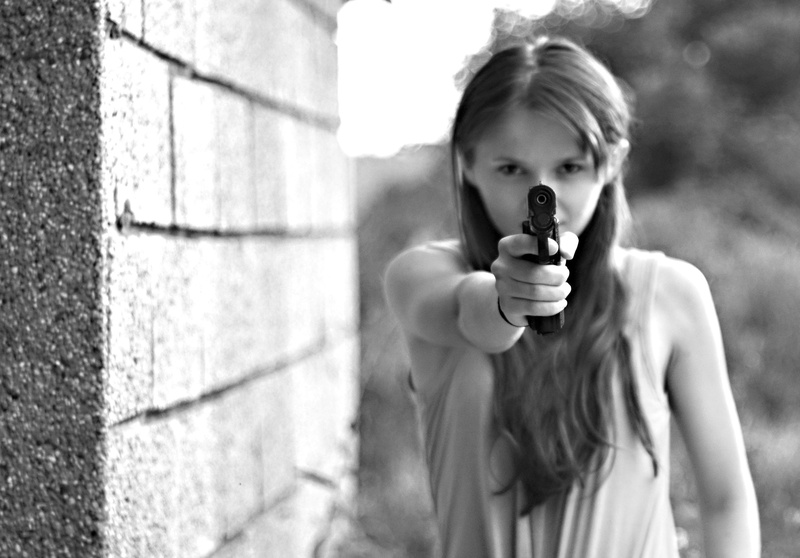 pointing, concrete, casual clothing, sleeveless, front view, wearing, girls, one person, outdoors, day, aiming, top, child, hint, aggression, weapon, pistol