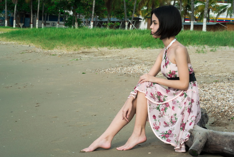 floral, girl, short hair, young adult, land, barefoot, dress, black hair, floral pattern, person, seating, fashion, one person, houses, driftwood, relaxation