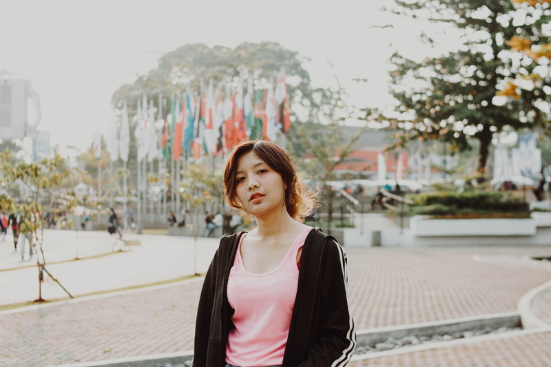 face, teenager, handrail, apparel, casual clothing, hairstyle, looking, young women, standing, flags, waist up, sleeve, focus on foreground, wearing, building exterior