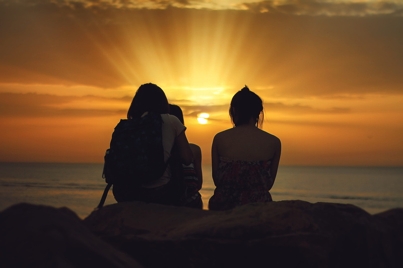 5K, sitting, woman, stone, adult, brown, land, water, looking at view, female, orange color, sunlight, three, horizon over water, watching, sea, women