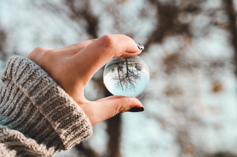 outdoors, warm clothing, sphere, one person, focus on foreground, tree, hand, 5K, crystal ball, macro, human hand, plant, winter, glass, human finger