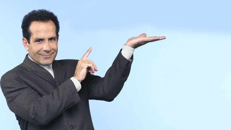 one person, finger, looking at camera, human arm, happiness, smiling, Tony Shalhoub, clothing, human hand, adult, waist up, front view, standing, blue