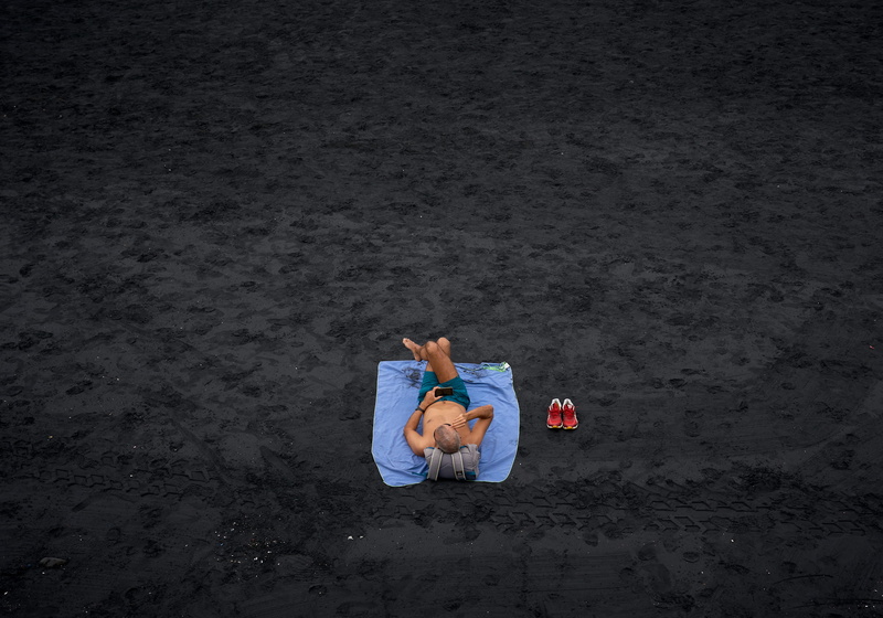 leisure activity, field, full length, beach, lying, mat, relax, picnic, black, ground, nature, sun, person, bathe, real people, shoe, man, smartphone, relaxation