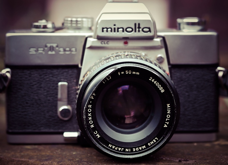 still life, rangefinder camera, equipment, text, focus on foreground, retro look, technology, old camera, antique, photograph, indoors, photography, silver colored